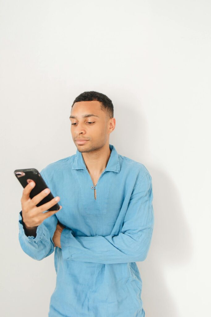 tanned man in a blue shirt scrolling social media for business on his mobile phone